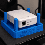 FRC 2025 Radio Mount 3D Print featuring a blue 3D-printed holder securing a white radio device. FRC 2025 Radio Mount 3D Print featuring a blue 3D-printed holder securing a white radio device.