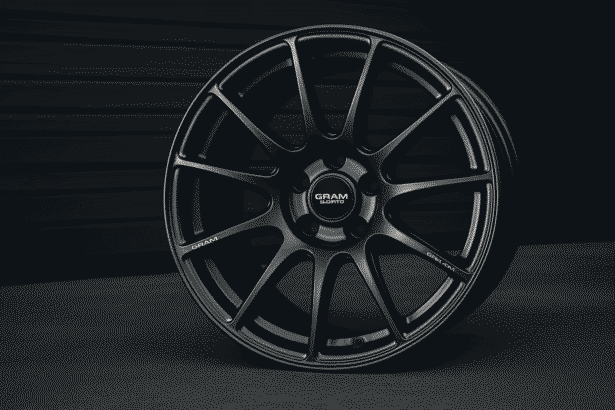 Close-up image of a sleek alloy wheel from Gram Lights placed against a dark background.